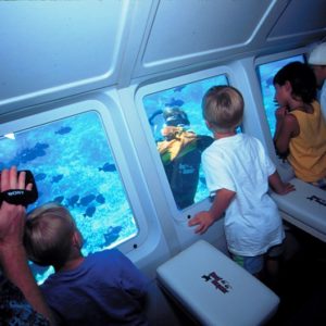 Kids on glass bottom boat watching scuba diver
